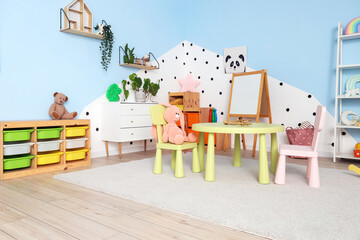 Poster - Interior of modern playroom in kindergarten with chest of drawers, shelving unit and table with chairs