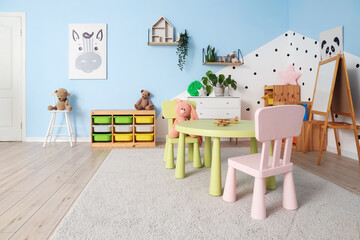 Poster - Interior of modern playroom in kindergarten with chest of drawers, shelving unit and table with chairs