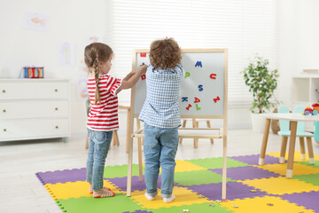 Poster - Cute little children learning alphabet with magnetic letters on board in kindergarten