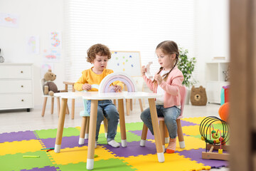 Poster - Cute little children playing with colorful toy rainbow at white table in kindergarten