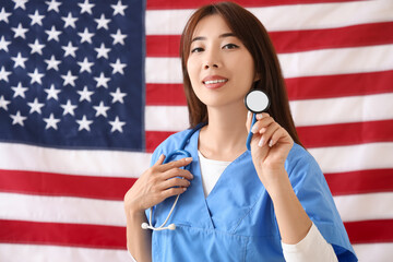 Wall Mural - Female Asian doctor with stethoscope against USA flag. Labour Day celebration