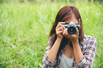 Wall Mural - Close up hands Asian Women look at dslr digital camera vintage film style take a photo. Professional female photographer look at picture outdoor. Young woman hands shooting photo in green nature park