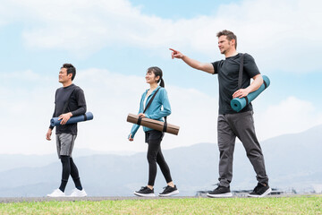 Poster - 青空の見える公園をヨガマットを持って歩くスポーツウェアの男女（ヨガ教室）
