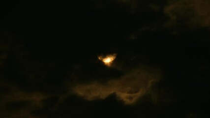 Wall Mural - a moon emerges from a dark night cloaked in thick clouds - wide shot