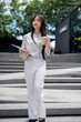 © bongkarn - A confident, beautiful Asian businesswoman is walking down the stairs outdoors in the city.
