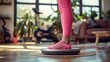 © Khritthithat - Woman in pink sportswear standing on scales, hands on hips, checking weight in a modern living room with fitness equipment, showcasing a healthy lifestyle