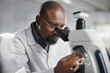 © peopleimages.com - Healthcare, microscope and science with man in lab for medical or pharmaceutical research. Innovation, sample and study with African scientist at work for analysis, development or experiment results