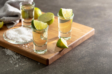 Wall Mural - Tequila with sea salt and lime slices on a cutting board.