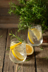 Wall Mural - Cocktail gin tonic with ice, lemon, and rosemary on a old wooden table.