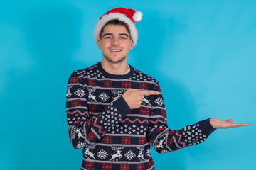 Poster - young man with santa claus hat isolated pointing on color background