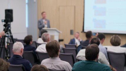 Wall Mural - business conference with a speaker and attendees seated in a meeting room. a camera operator records
