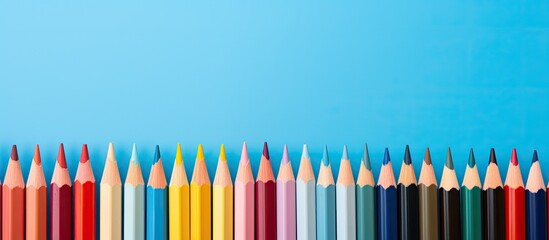 Poster - Colorful pencils lined up against a blue backdrop with copy space image.