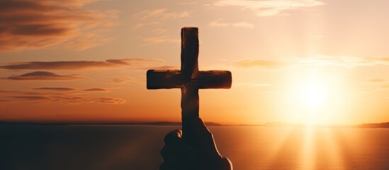Poster - A person praying and holding a Christian cross in worship with a sunset copy space image for a religious background.