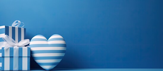 Wall Mural - A white heart and two gift boxes with blue stripes are seen on a blue backdrop, leaving room for a copy space image.