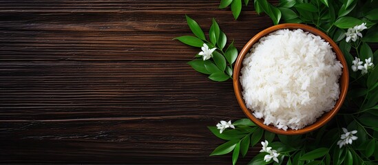 Aufkleber - Top-down perspective of Jasmine rice displayed on a dark wooden surface among lush green plants, featuring jasmine rice served in a wooden bowl with copy space image.