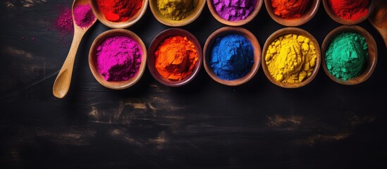 Poster - Aerial view of vibrant Holi paint powder in wooden bowls on a dark concrete backdrop, offering copy space image for text. Celebrating the Indian festival of colors, Holi.
