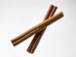 Two cinnamon sticks crossed on a white background