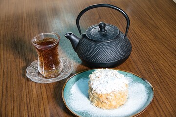 Black Tea, Cake, and Teapot on Wooden Table