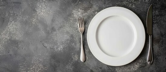 Poster - Gray stone concrete table with an empty white ceramic plate, knife, and fork. Perfect for menu or recipe concepts with copy space image.
