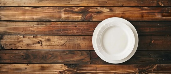 Poster - Wooden table with a white plate, showcasing a copy space image.