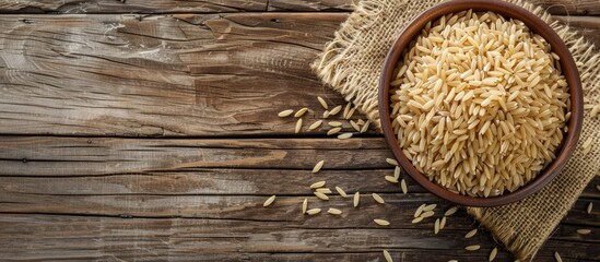 Wall Mural - Top view of uncooked long brown rice on a wooden table with copy space image.