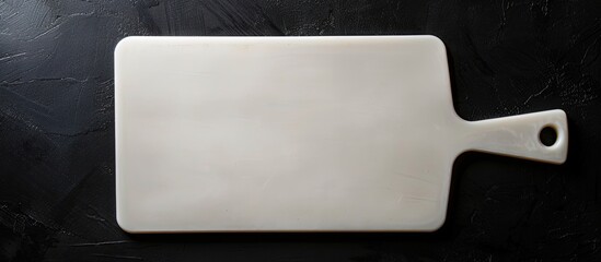 Wall Mural - An empty white cutting board showcased against a black background with copy space image.