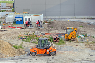 Wall Mural - Road Roller and Backhoe Digger at Construction Site New Factory Building