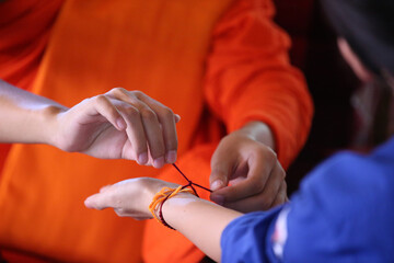 Sticker -  Wat Si Muang ( Simuong) buddhist temple.  Buddhist ceremony.  Monk ties blessed cotton bracetet ( Sai-sin) around a wrist. Vientiane. Laos;