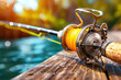 © weerasak - Close-up of a fishing rod with a yellow line on a wooden pier by the water, bathed in sunlight. Perfect summer fishing day.