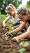 © Mind - Two young girls are focused on planting seedlings in a garden. They are working in a row of soil on a bright, sunny day.