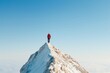 © artitwpd - A man stands alone on a snow-capped mountain peak. He is wearing a red jacket and black pants. The sky is clear and blue. The sun is shining brightly. The man is looking out at the view.