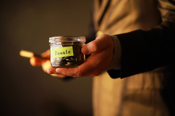 Sticker - Businessman hand putting money (coin) in the glass jar, vintage tone effect