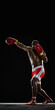 © master1305 - Full-length image of muscular man, shirtless boxer in red shorts and gloves training Jab punch. isolated on black background. Concept of sport, active lifestyle, body, strength. Vertical poster