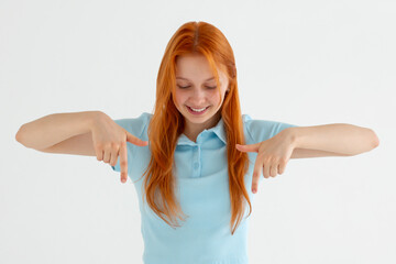 Wall Mural - Excited brunette woman checking out awesome news, pointing fingers down and staring amazed, showing advertisement on bottom copy space, standing against white background