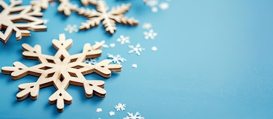 Poster - Close-up view of decorative wooden Christmas snowflakes on a blue background, creating a festive New Year card with creative copy space image.