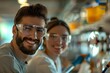 © Vera - Portrait of beautiful male and female janitors wearing glasses and with cleaning equipment, the man with a well groomed beard, smiling and laughing.