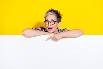 Poster - Photo portrait of lovely senior lady point down empty space dressed stylish colorful garment isolated on yellow color background