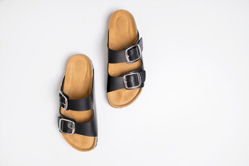 Black leather sandals with cork soles on a white background, top view flat lay. Trendy fashionable summer clogs, unisex sandals. Minimalism style