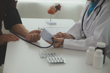 Wall Mural - Doctor using sphygmomanometer with stethoscope checking blood pressure to a patient in the hospital.