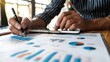 © Tida - Businessman Analyzing Financial Data with Graphs - A businessman in a striped shirt analyzes financial data with graphs, using a pen and a digital tablet. - A businessman in a striped shirt analyzes f