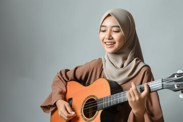 Dedication of kid learning music, musical education, talent development concept. Muslim girl playing an acoustic guitar with focus and concentration on white studio background