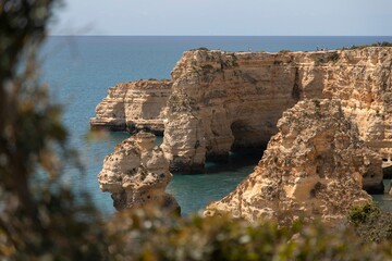 Sticker - Scenic view of a sandy beach with rocky cliffs and clear blue water in Algarve, Portugal