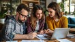 © Vitalii Shkurko - Three colleagues collaborating on a project in a modern office, discussing ideas and working together with a laptop and documents.