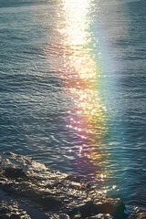 Wall Mural - sun beams reflecting on rainbow, rippling ocean