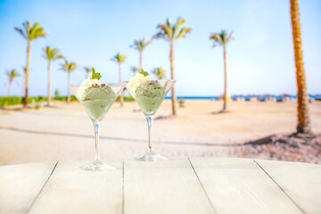 Sticker - Ice cream with mint and vanilla flavour in glass cups fruit delicious and cooling on a hot day on a tropical beach. Place for advertising products.