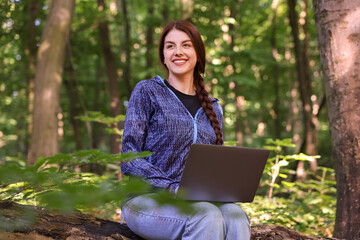 Wall Mural - Smiling freelancer working with laptop in forest. Remote job