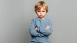 © Abdul - Mad male kid, angry little boy standing with his arms crossed, and looking at the camera with upset face expression. Unhappy toddler, studio shot, annoyed and frustrated child emotion, copy space
