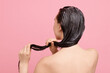 © New Africa - Woman applying hair mask on pink background, back view