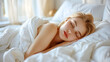 © Kakabe - Peaceful young woman sleeping in a cozy bed, surrounded by soft white bedding and gentle morning light filtering through the window.