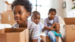 © Nawapol - Family packing boxes in a living room with children helping